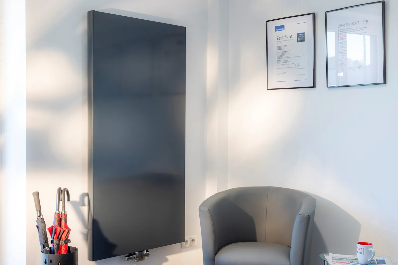 Moderner anthrazitfarbener Flachheizkörper an einer hellen Wand