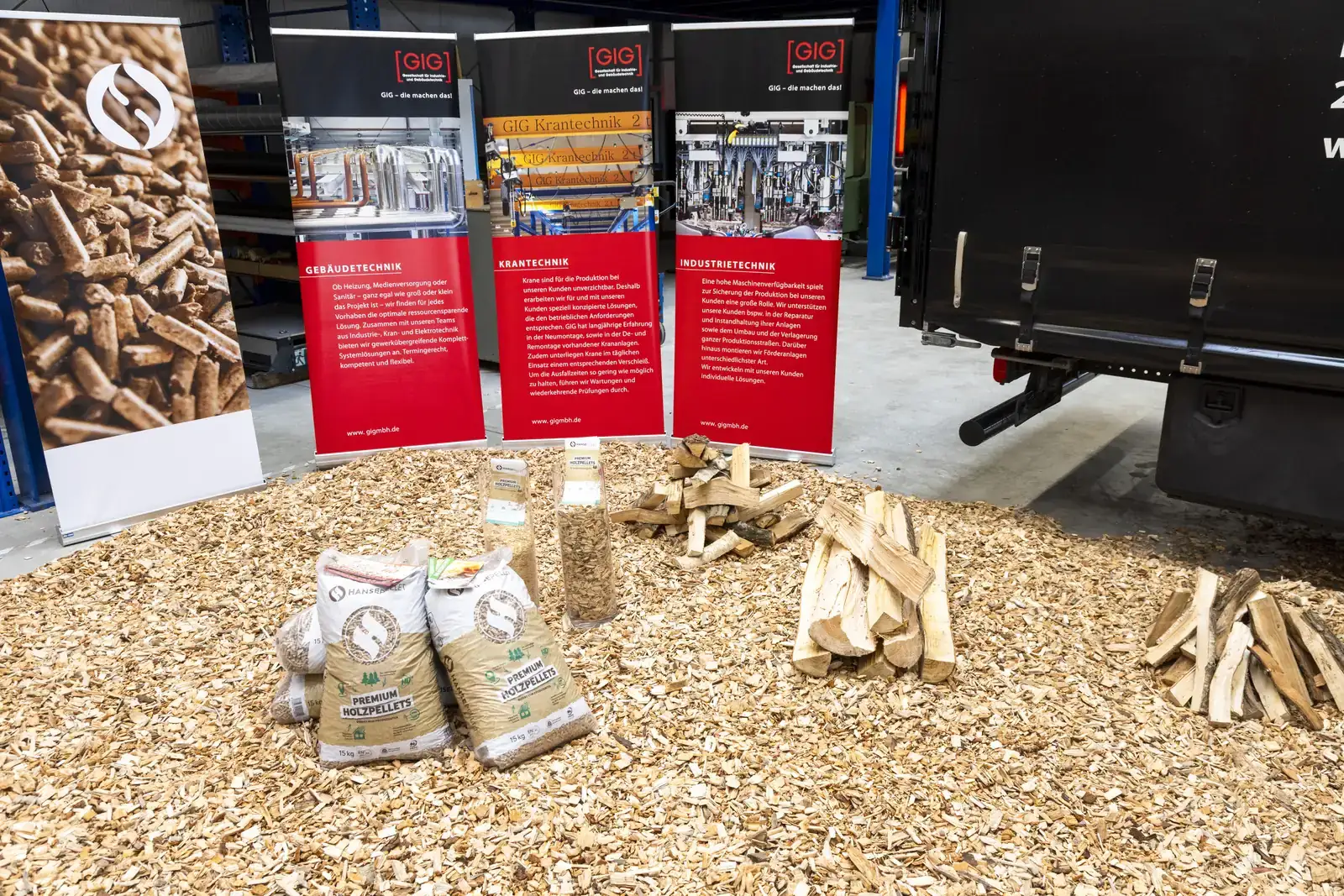 Holzpellets in Säcken, gespaltenes Scheitholz und Hackschnitzel nebeneinander