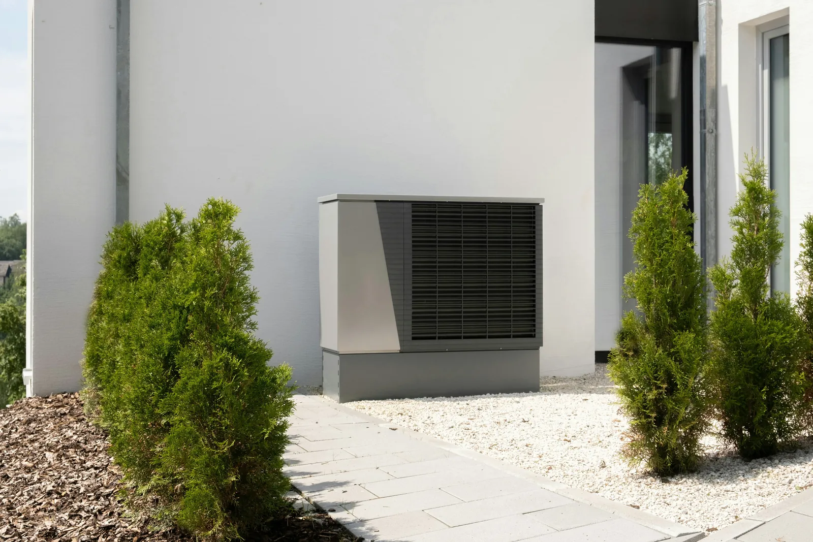 Außengerät einer Luft-Wasser-Wärmepumpe an der Hauswand eines Wohnhauses